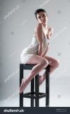 stock-photo-attractive-woman-in-short-skirt-and-sexy-posing-sitting-on-chair-83144560.jpg